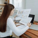 Woman reviewing business charts in a home office setting, showcasing remote work lifestyle.